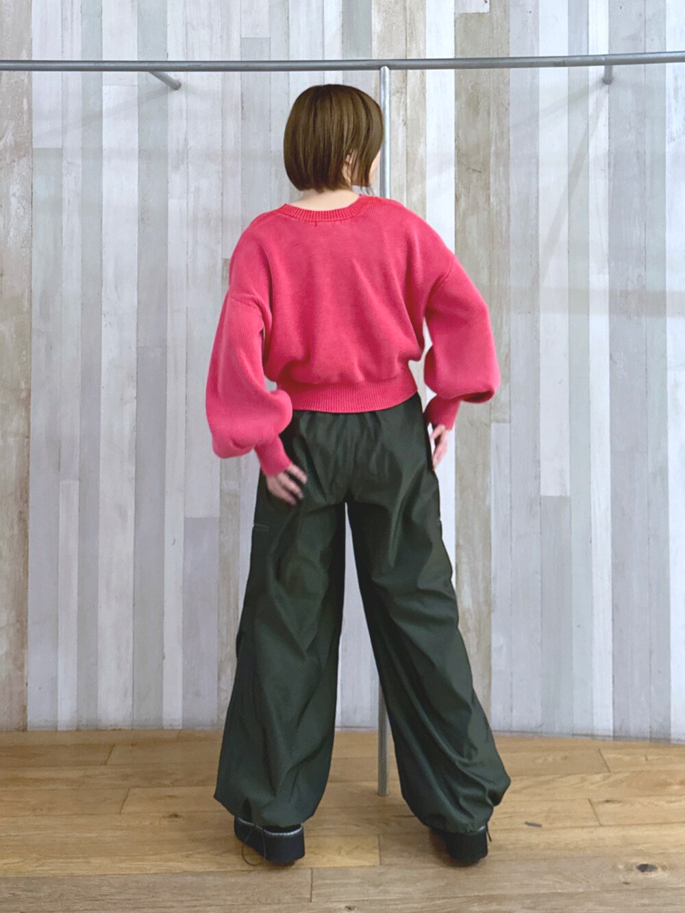 レッド系のニット/セーター、グリーン系のカーゴパンツ、ブラック系のブーツを着用したレディースの冬コーディネートの2枚目の写真