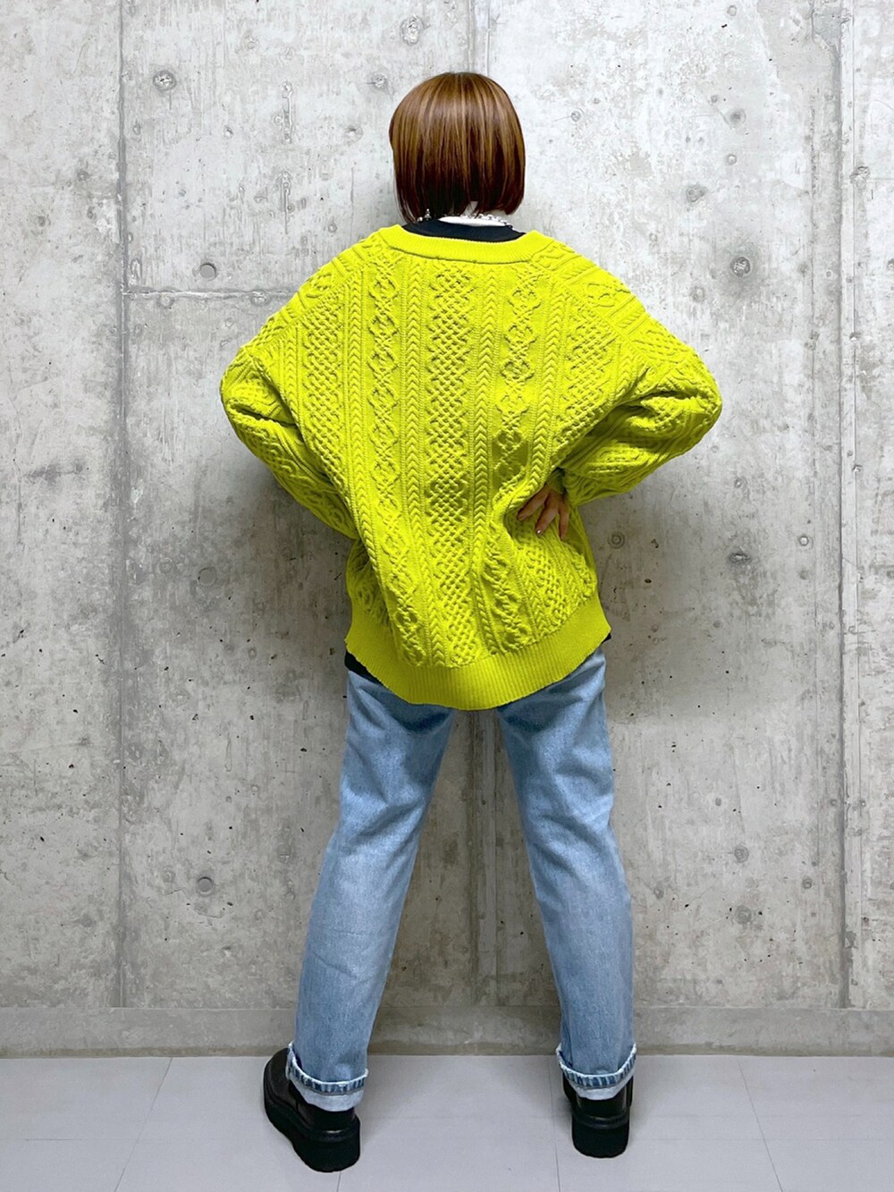 ブラック系のTシャツ/カットソー、イエロー系のニット/セーター、ブルー系のデニムパンツを着用したレディースの冬コーディネートの2枚目の写真