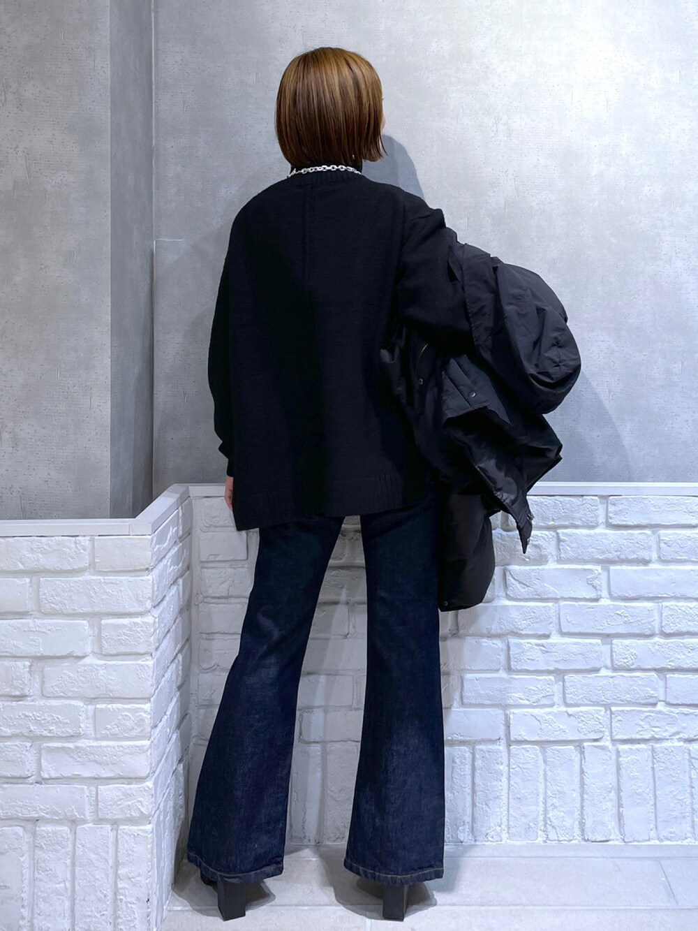 ブラック系のニット/セーター、ピンク系のボストンバッグ、ブラック系のブルゾンを着用したレディースの冬コーディネートの2枚目の写真