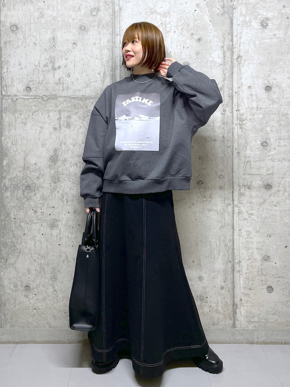 グレー系のスウェット、ブラウン系のブルゾン、ブラック系のトートバッグを着用したレディースの冬コーディネートの2枚目の写真