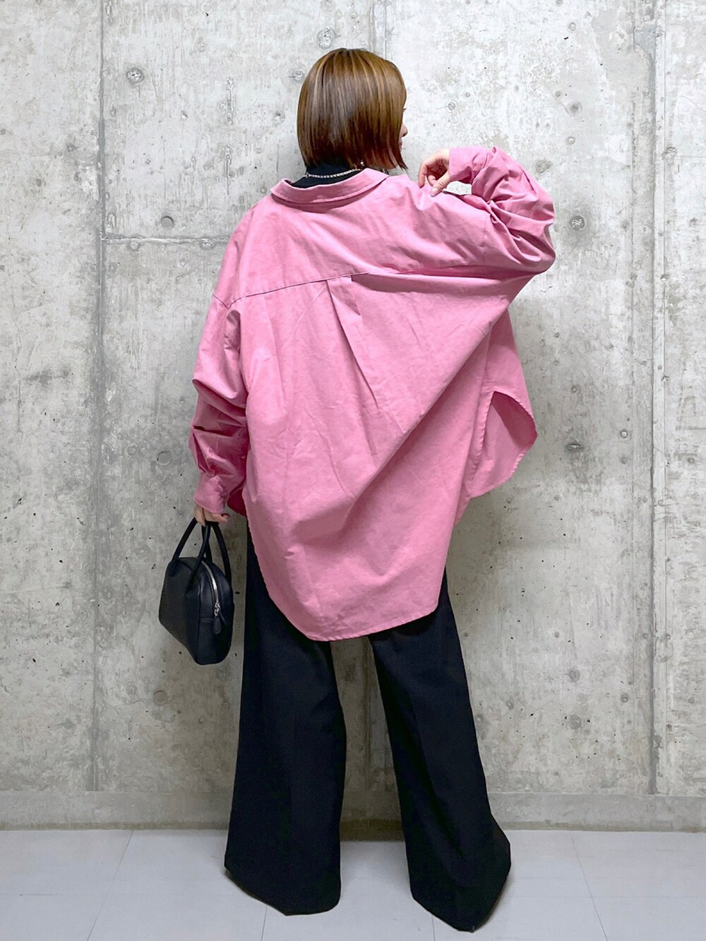 ブラック系のニット/セーター、ブルー系のシャツ/ブラウス、ブラック系のボストンバッグを着用したレディースの冬コーディネートの4枚目の写真