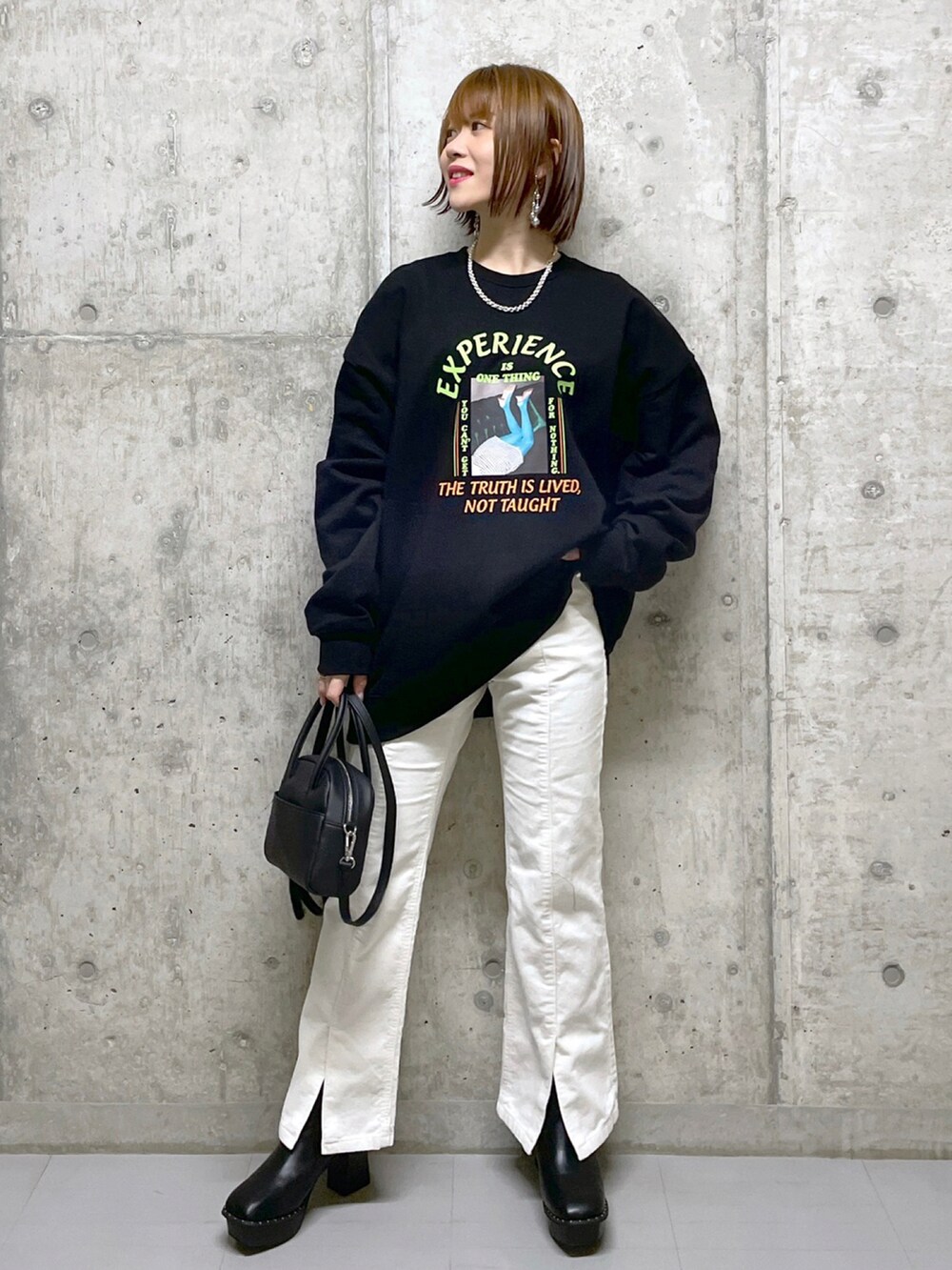 ブラック系のスウェット、ブルー系のニット/セーター、ブラック系のボストンバッグを着用したレディースの冬コーディネートの3枚目の写真