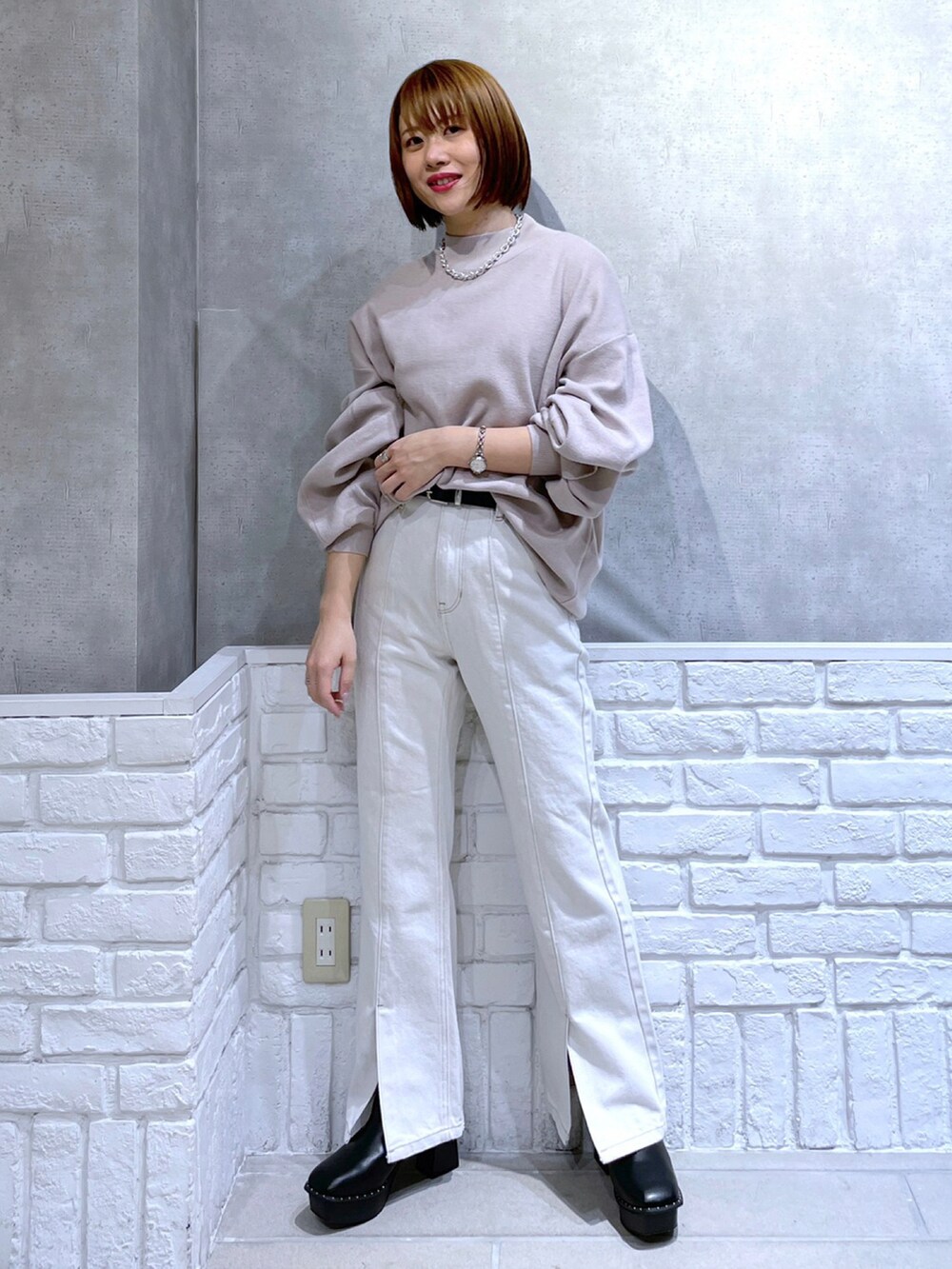 ベージュ系のニット/セーター、ブラック系のその他アウター、ホワイト系のデニムパンツを着用したレディースの冬コーディネートの2枚目の写真