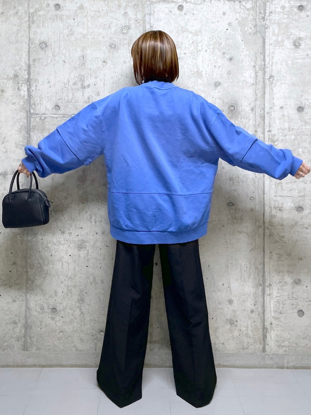 ブルー系のスウェット、ブラック系のボストンバッグ、ブラック系のニット/セーターを着用したレディースの冬コーディネートの3枚目の写真