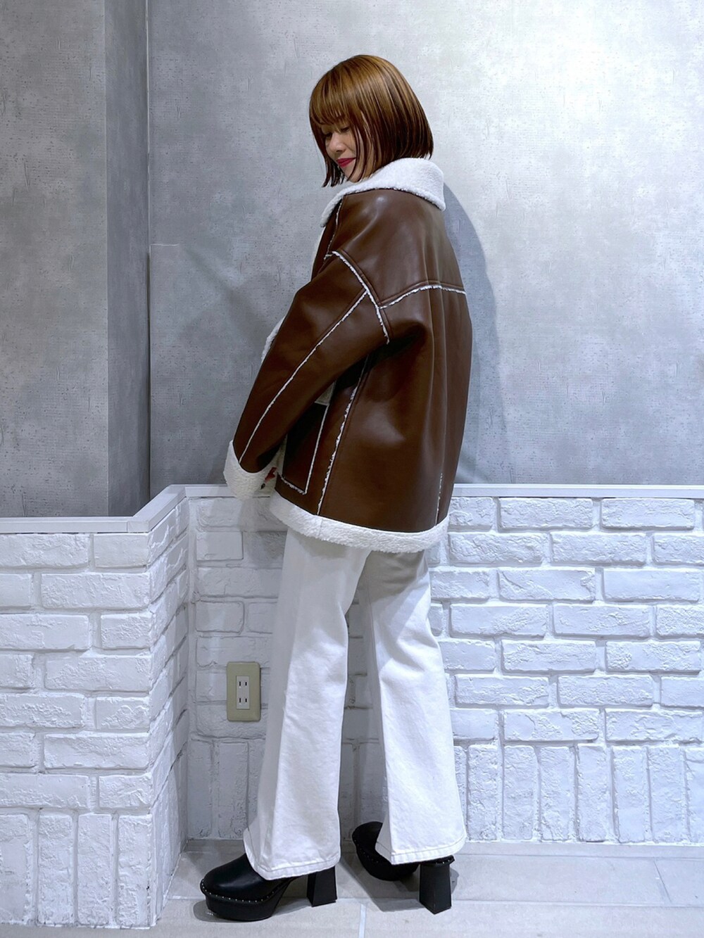 ブラウン系のブルゾン、ホワイト系のデニムパンツ、ブラック系のブーツを着用したレディースの冬コーディネートの3枚目の写真