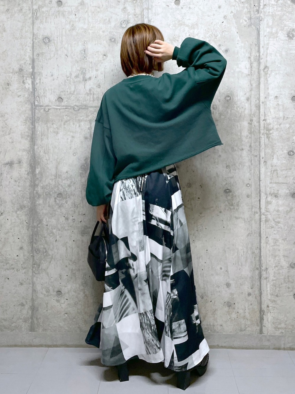 グリーン系のスウェット、ホワイト系のスカート、ブラック系のボストンバッグを着用したレディースの冬コーディネートの2枚目の写真