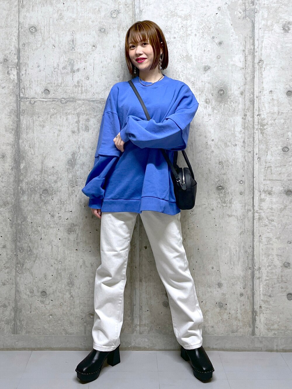 ブルー系のスウェット、ホワイト系のデニムパンツ、ブラック系のブーツを着用したレディースの冬コーディネートの2枚目の写真