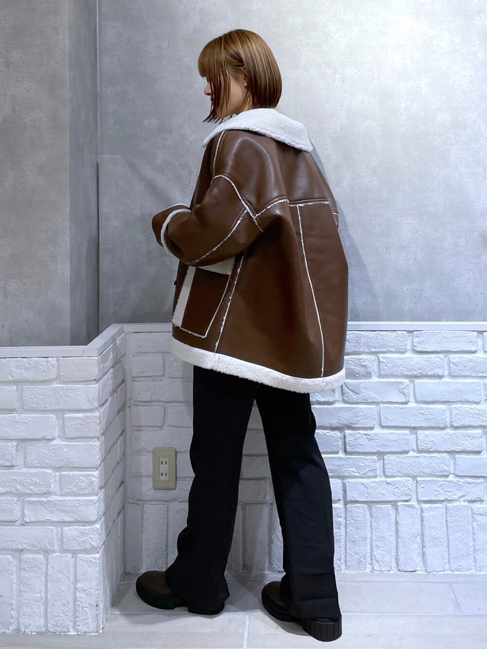 ブラウン系のブルゾン、ホワイト系のスウェット、ブラック系のスラックスを着用したレディースの冬コーディネートの3枚目の写真