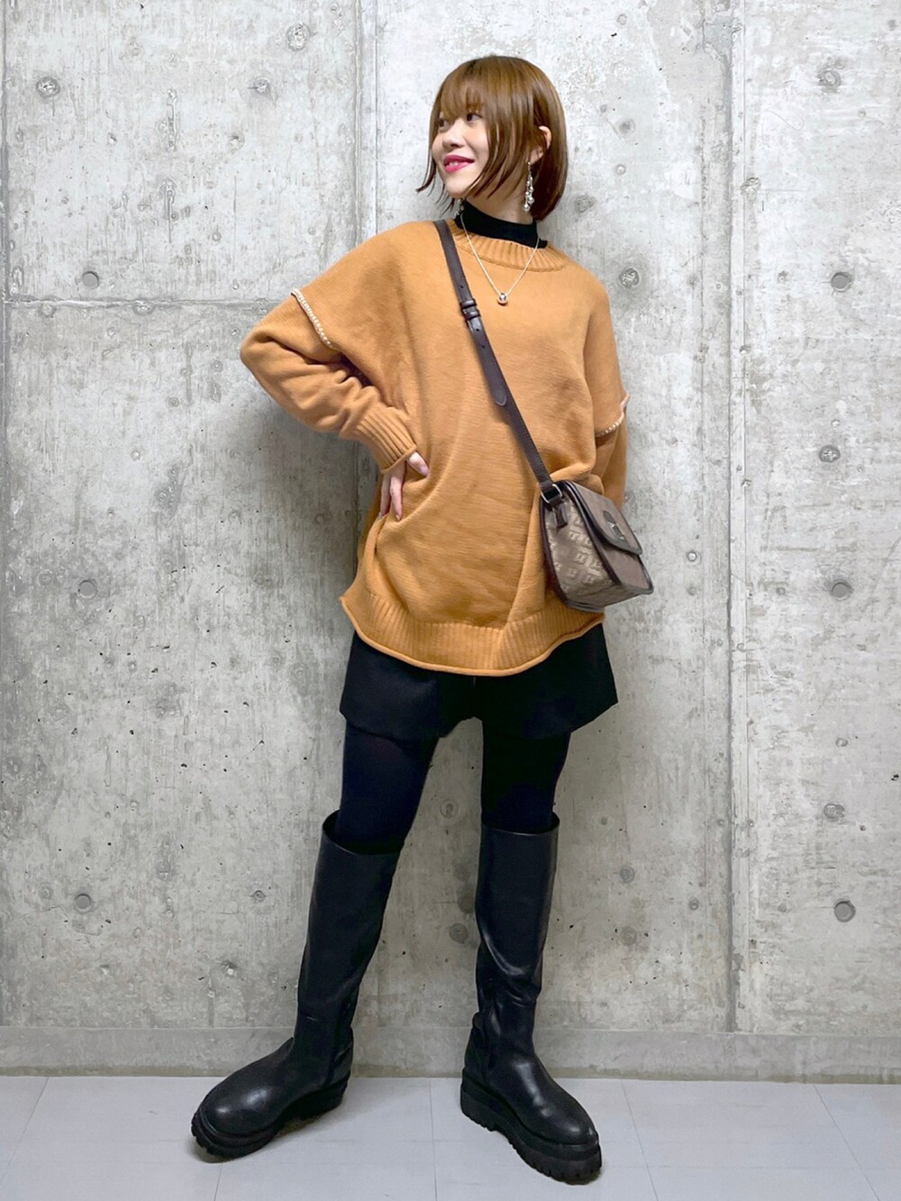 オレンジ系のニット/セーター、ブラック系のニット/セーター、ブラウン系のショルダーバッグを着用したレディースの冬コーディネートの4枚目の写真