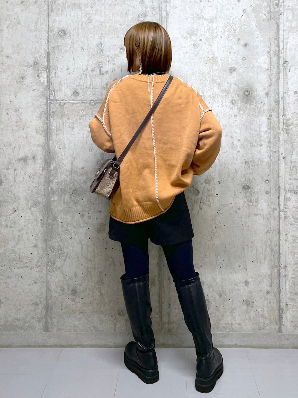 オレンジ系のニット/セーター、ブラック系のニット/セーター、ブラウン系のショルダーバッグを着用したレディースの冬コーディネートの5枚目の写真