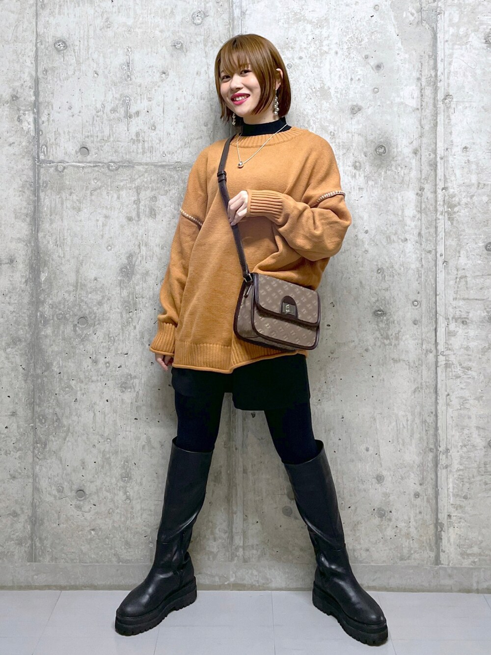 オレンジ系のニット/セーター、ブラック系のニット/セーター、ブラウン系のショルダーバッグを着用したレディースの冬コーディネートの3枚目の写真