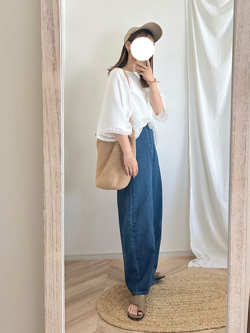 ホワイト系のトップス、ブルー系のパンツ、ブラウン系のサンダルを着用したレディースの春コーディネートの2枚目の写真