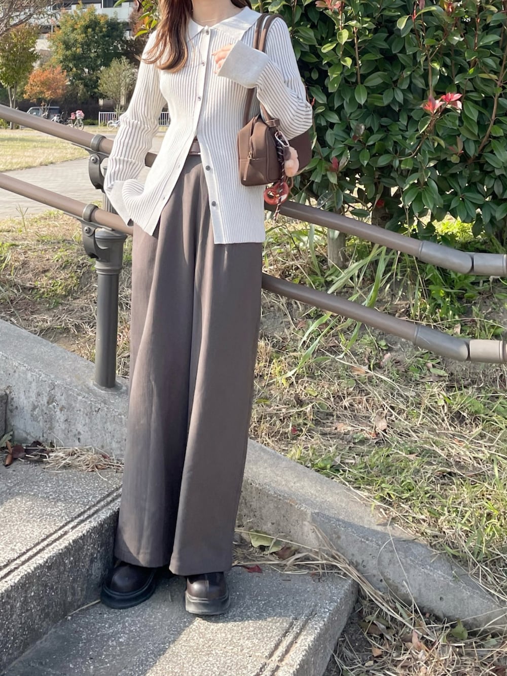 ホワイト系のニット/セーター、グレー系のパンツ、ブラウン系のブーツを着用したレディースの秋コーディネートの2枚目の写真