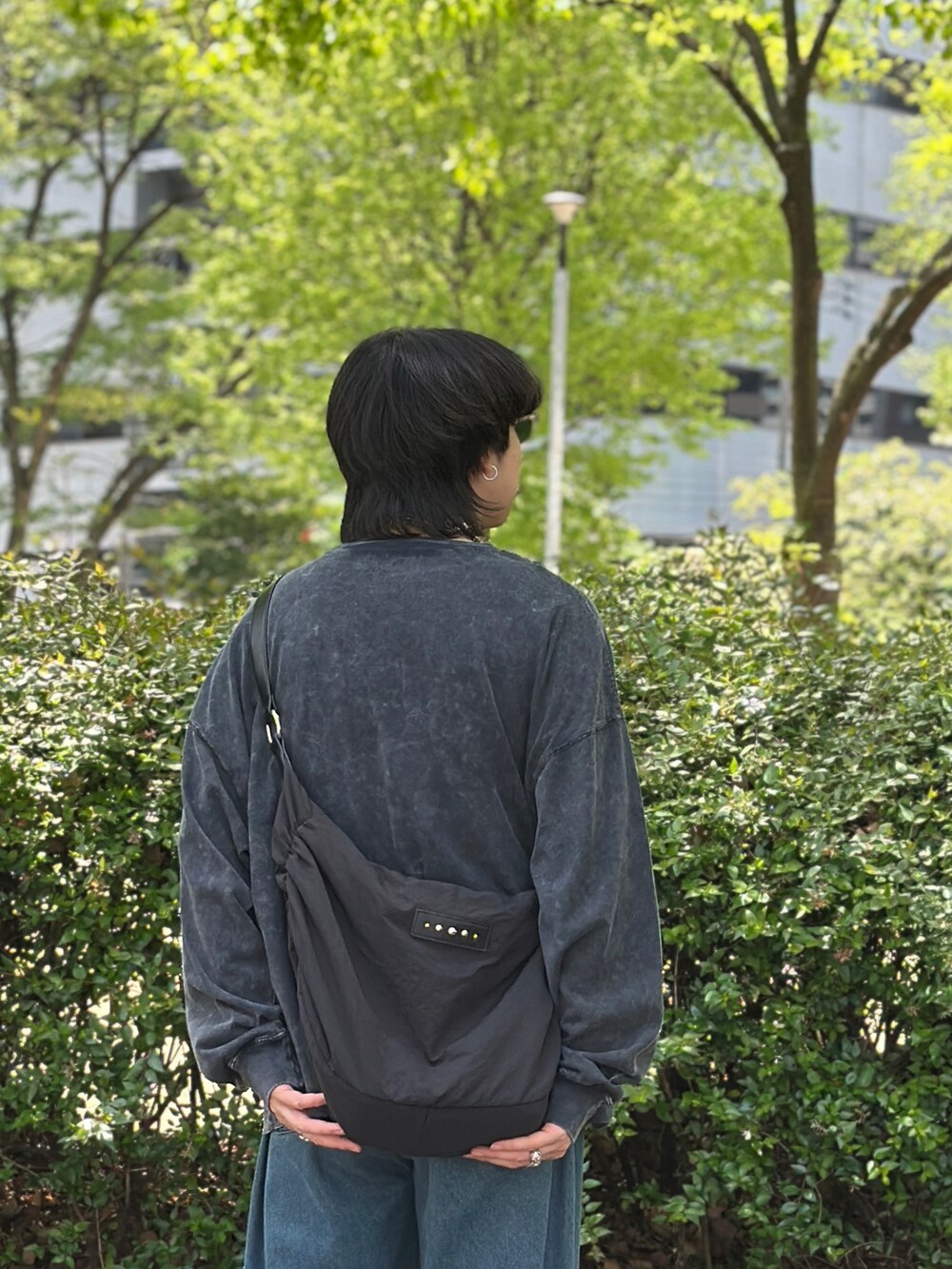 ブラック系のTシャツ/カットソー、ブラック系のショルダーバッグ、ブルー系のデニムパンツを着用したメンズの春コーディネートの3枚目の写真