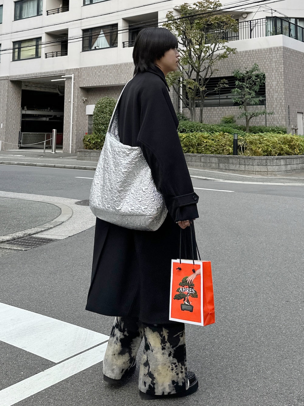 ブラック系のステンカラーコート、シルバー系のショルダーバッグ、その他のパンツを着用したメンズの秋コーディネートの2枚目の写真