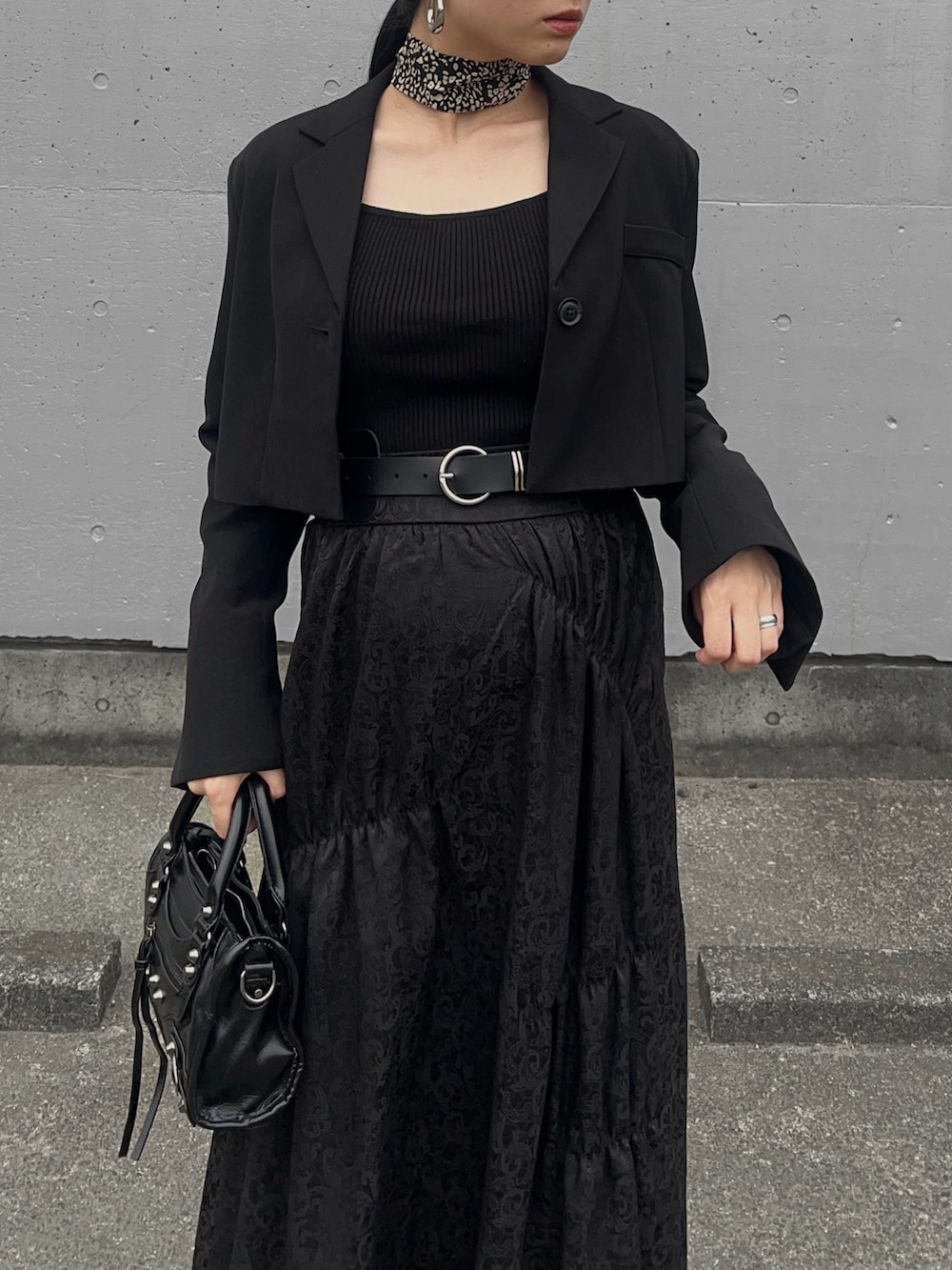 ブラック系のテーラードジャケット、ブラック系のニット/セーター、ブラック系のスカートを着用したレディースの春コーディネートの3枚目の写真