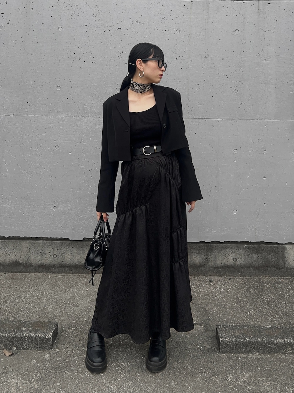 ブラック系のテーラードジャケット、ブラック系のニット/セーター、ブラック系のスカートを着用したレディースの春コーディネートの2枚目の写真