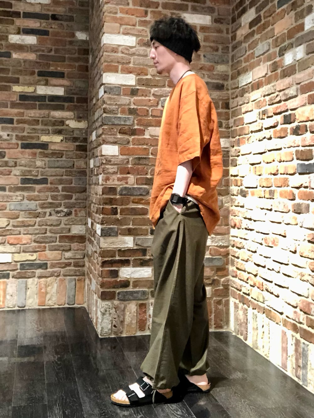 オレンジ系のトップス、グリーン系のその他パンツ、ブラック系のサンダルを着用したメンズの春コーディネートの2枚目の写真