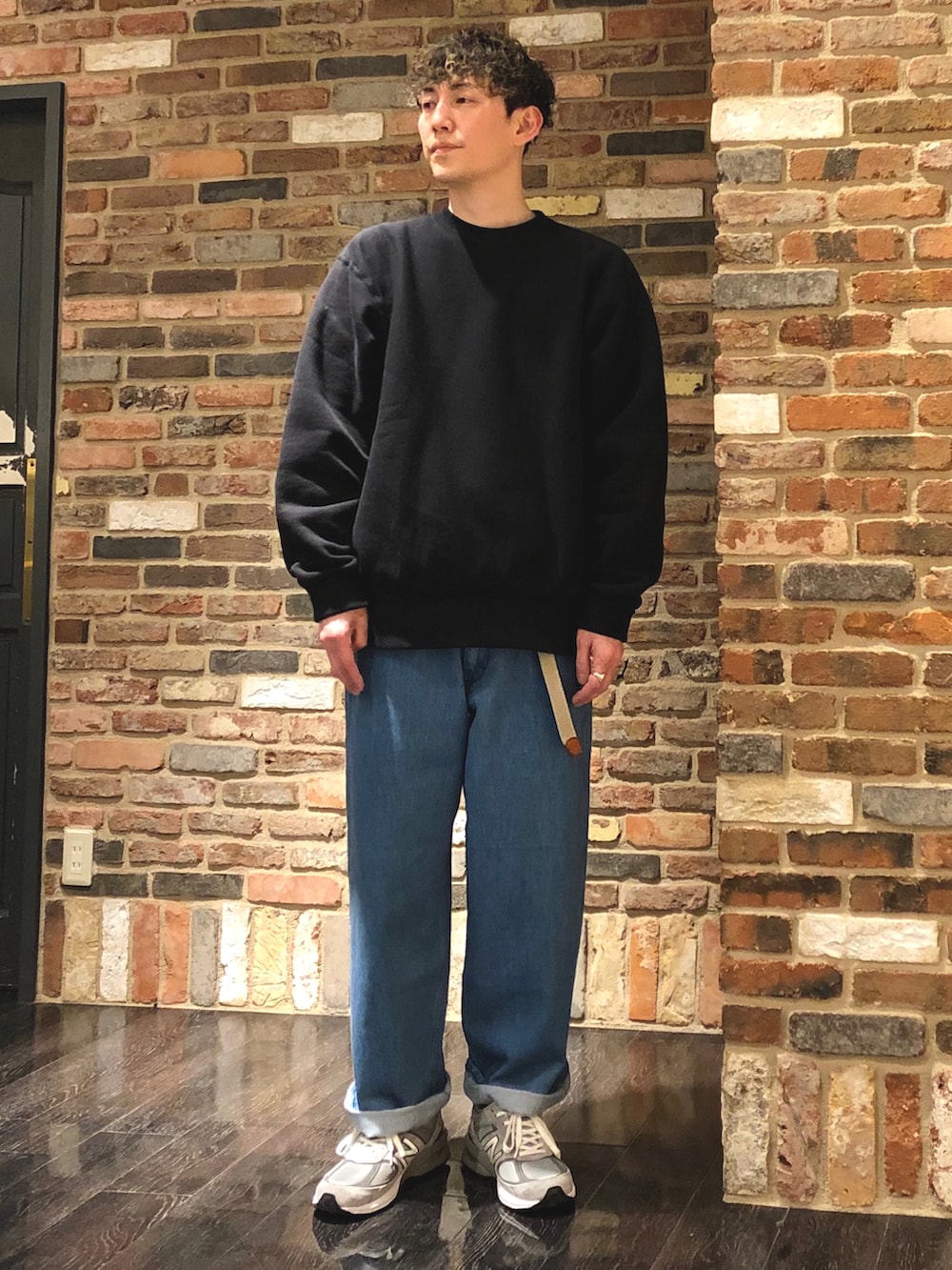 ブラック系のスウェット、ブルー系のデニムパンツ、グレー系のスニーカーを着用したメンズの春コーディネートの3枚目の写真