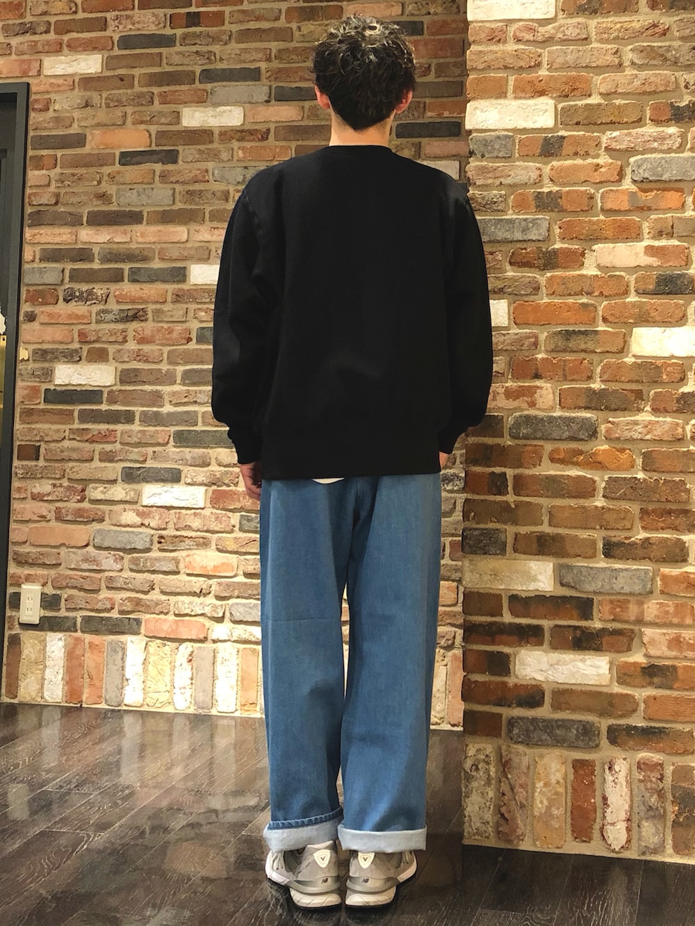 ブラック系のスウェット、ブルー系のデニムパンツ、グレー系のスニーカーを着用したメンズの春コーディネートの2枚目の写真