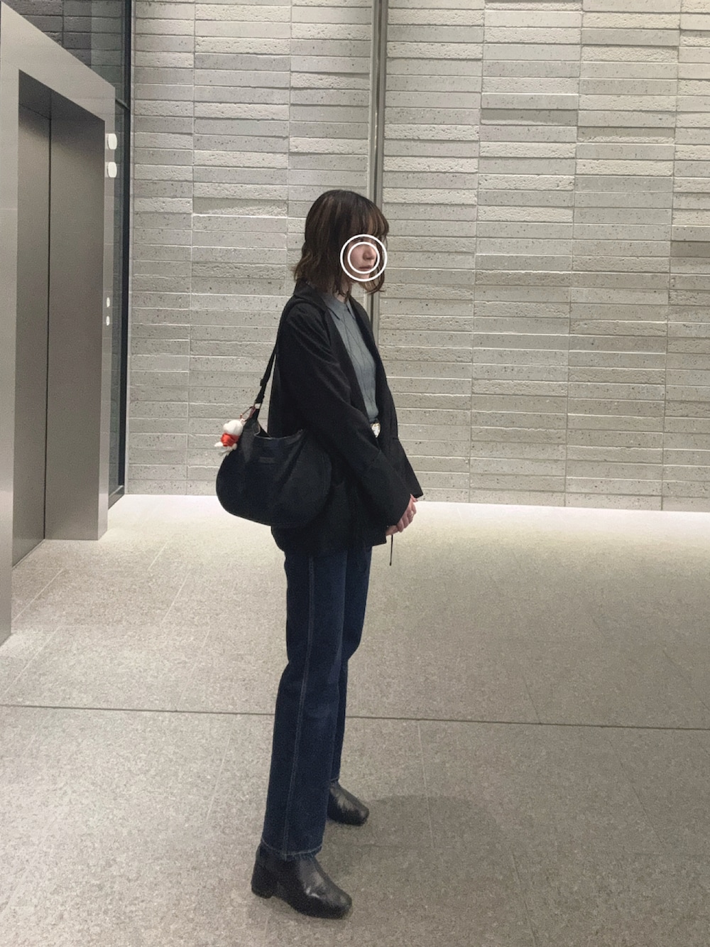 ブラック系のテーラードジャケット、ブルー系のデニムパンツ、ブラック系のブーツを着用したレディースの秋コーディネートの2枚目の写真