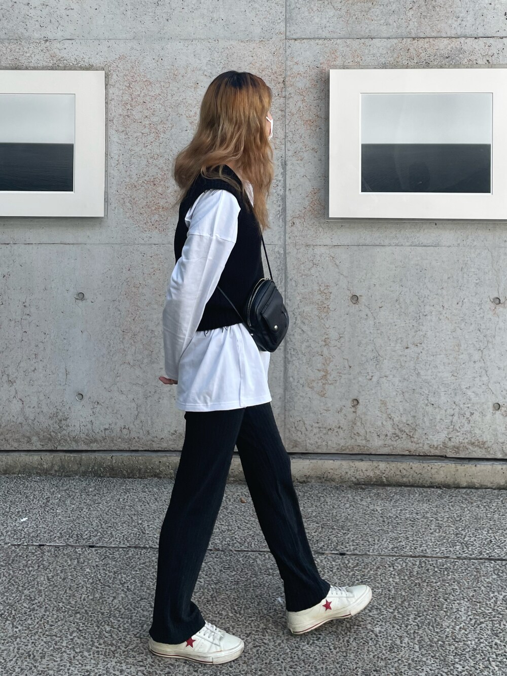 ホワイト系のスニーカー、ブラック系のベストを着用したレディースの秋コーディネートの2枚目の写真