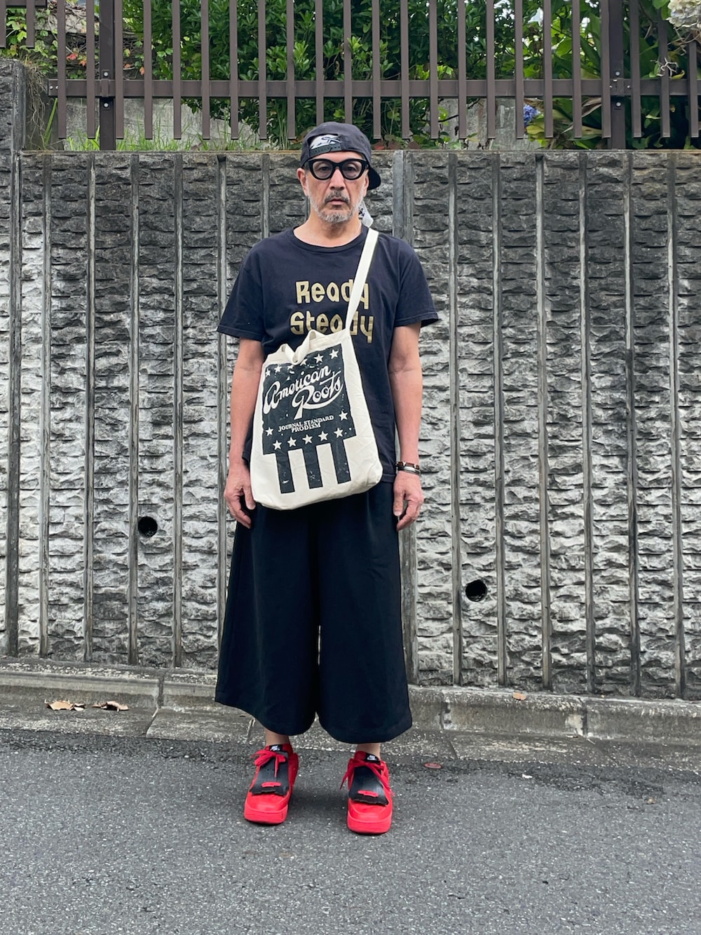 ブラック系のパンツ、レッド系のスニーカーを着用したメンズの夏コーディネートの2枚目の写真