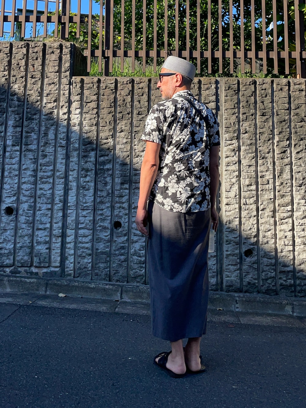 グレー系のその他パンツ、ブラック系のサンダル、ブルー系の帽子を着用したメンズの夏コーディネートの2枚目の写真