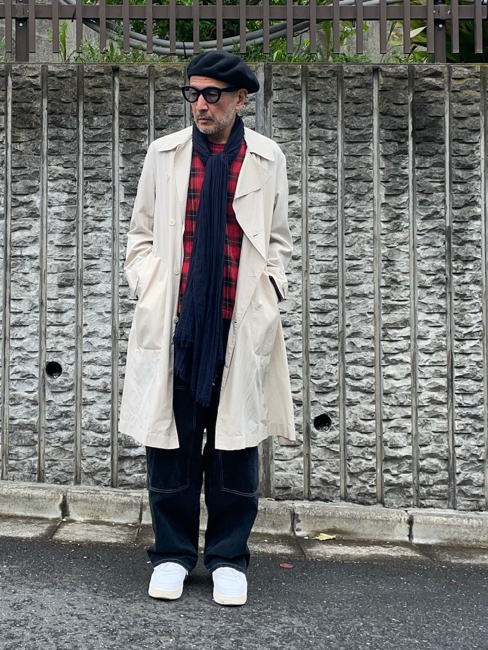 ベージュ系のトレンチコート、ブラック系のデニムパンツ、ブラック系の帽子を着用したメンズの春コーディネートの2枚目の写真