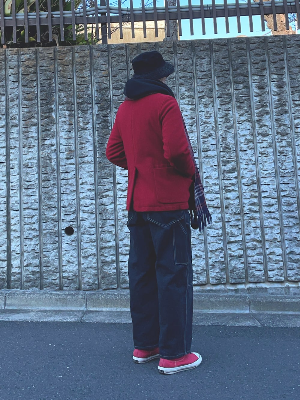 ブラック系のデニムパンツ、レッド系のミリタリージャケット、ブルー系のマフラーを着用したメンズの冬コーディネートの2枚目の写真