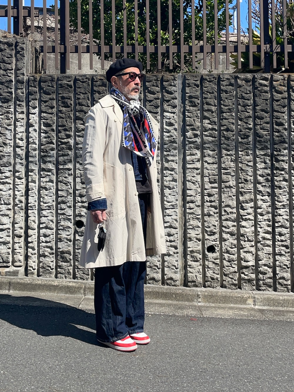 ベージュ系のトレンチコート、ブルー系のデニムジャケット、ブルー系のデニムパンツを着用したメンズの春コーディネートの2枚目の写真