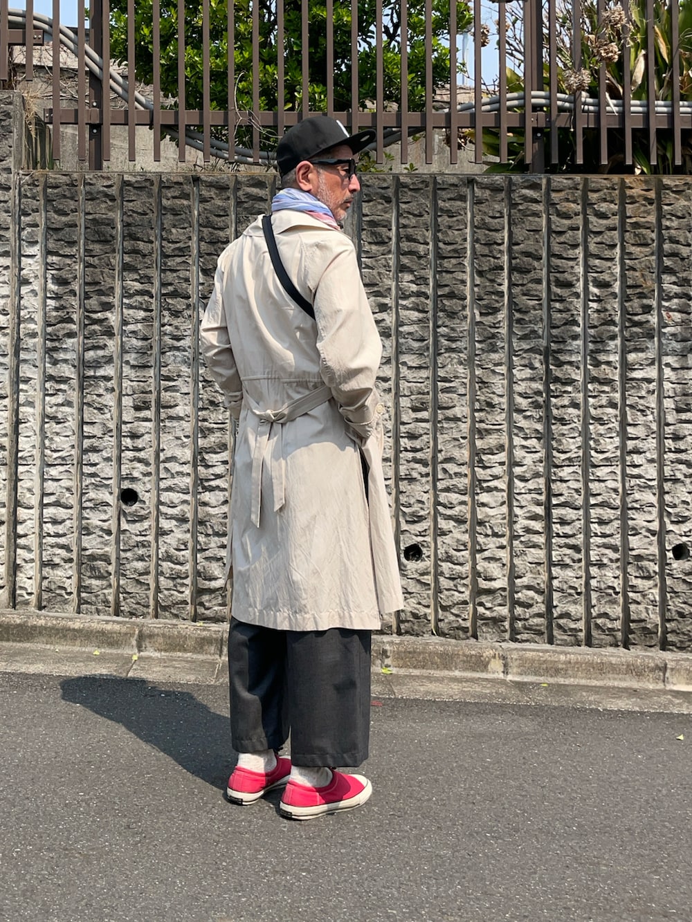 ベージュ系のトレンチコート、グレー系のパンツ、ホワイト系のTシャツ/カットソーを着用したメンズの春コーディネートの2枚目の写真