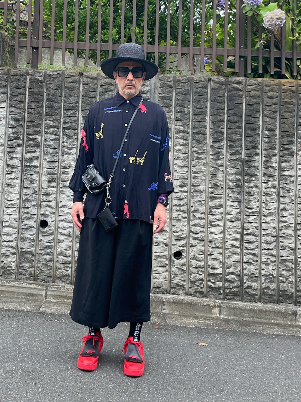 レッド系のスニーカー、ブラック系のパンツ、ブラック系のシャツ/ブラウスを着用したメンズの夏コーディネートの3枚目の写真