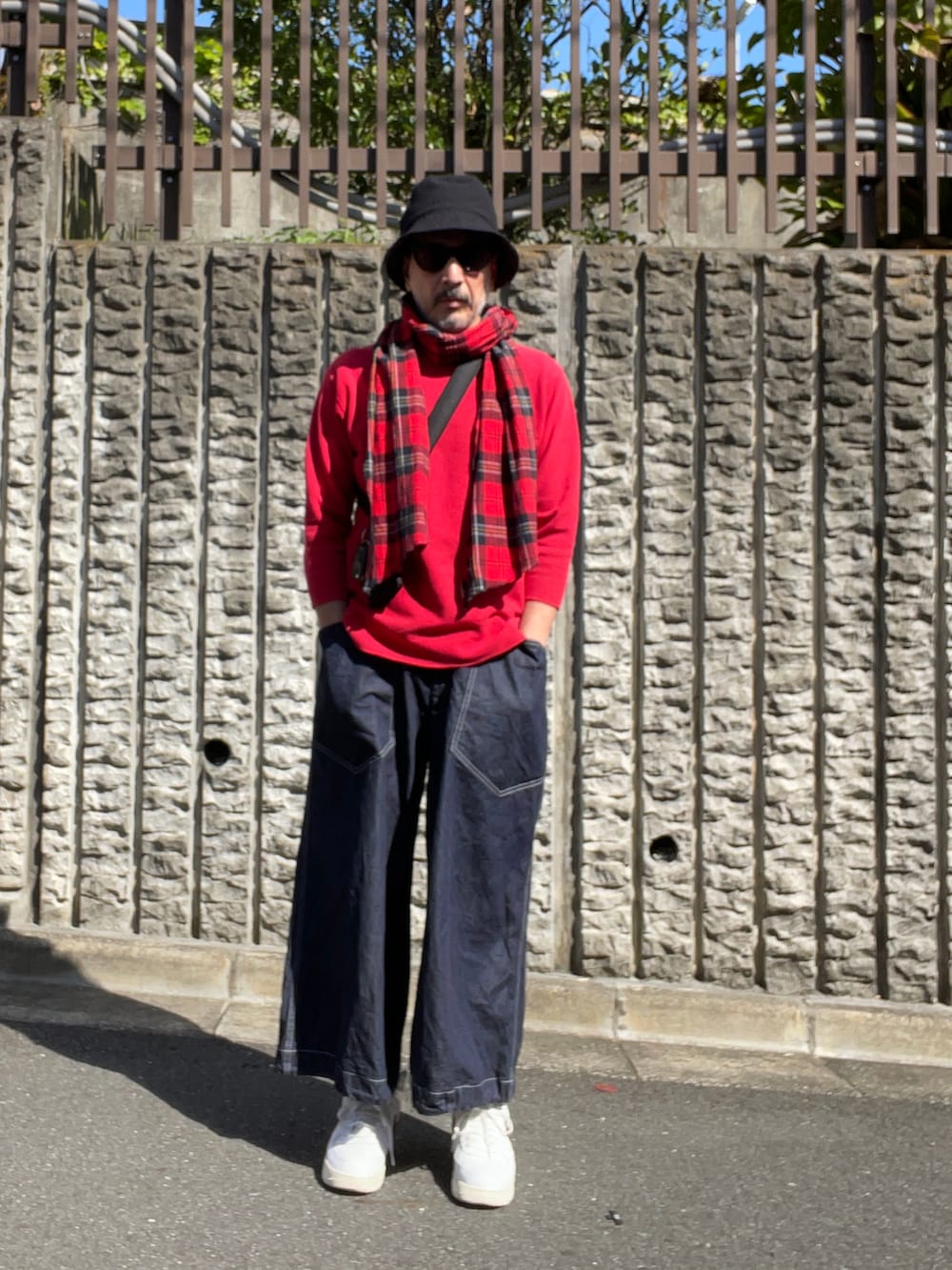 ブルー系のデニムパンツ、ホワイト系のスニーカー、ブルー系のハットを着用したメンズの秋コーディネートの2枚目の写真