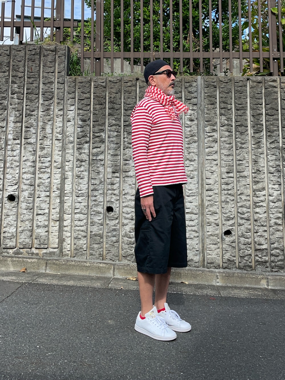 レッド系のTシャツ/カットソー、ブラック系のパンツ、ホワイト系のスニーカーを着用したメンズの秋コーディネートの2枚目の写真