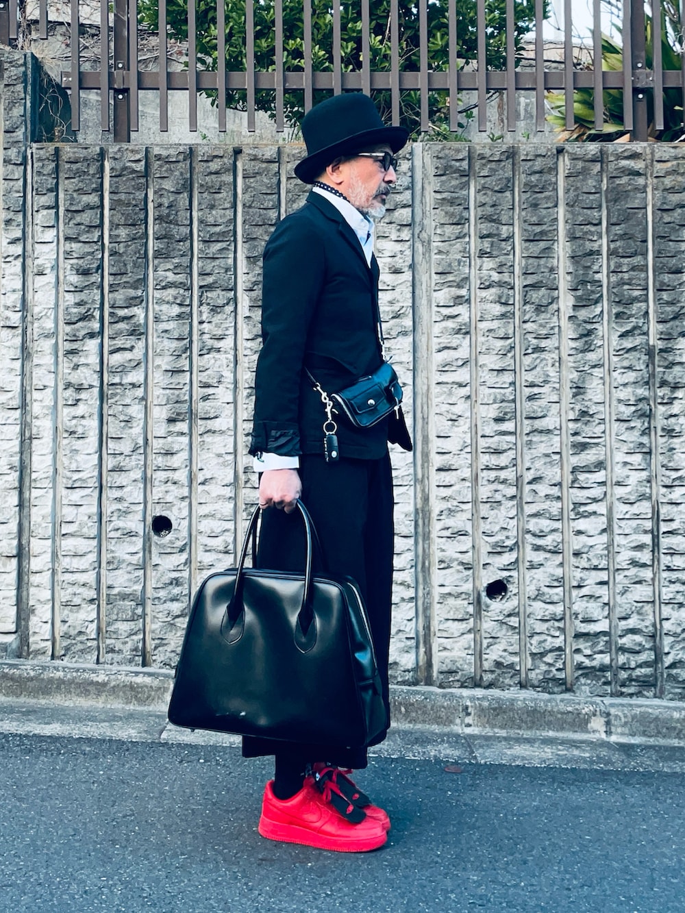 ブラック系のテーラードジャケット、レッド系のスニーカー、ブラック系のバッグを着用したメンズの春コーディネートの2枚目の写真