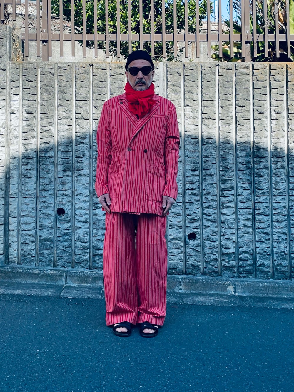 レッド系のテーラードジャケット、レッド系のパンツ、レッド系のストール/ショールを着用したメンズの冬コーディネートの2枚目の写真