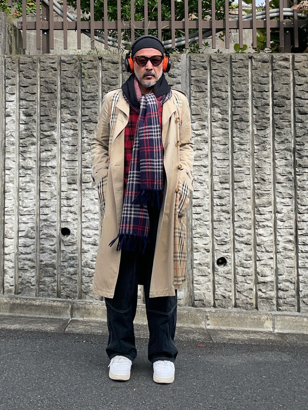 ベージュ系のトレンチコート、ブラック系のデニムパンツ、ホワイト系のスニーカーを着用したメンズの秋コーディネートの2枚目の写真