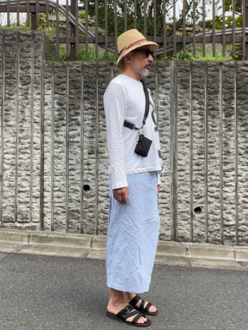 ホワイト系のTシャツ/カットソー、ブラック系のサンダル、ベージュ系のハットを着用したメンズの秋コーディネートの2枚目の写真