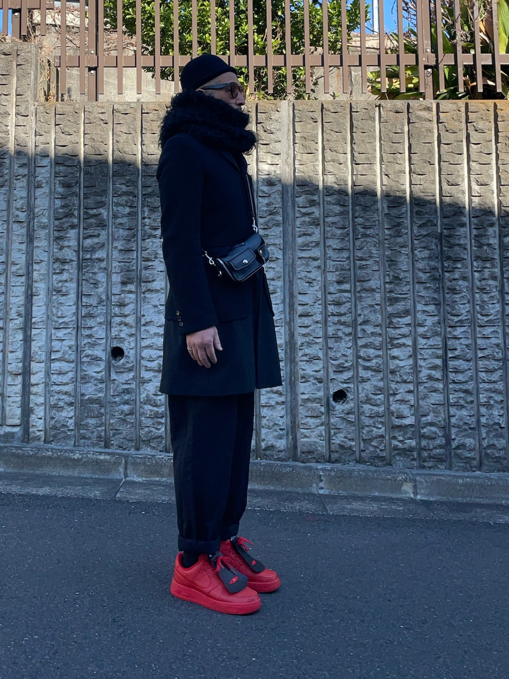 ブラック系のテーラードジャケット、ブラック系のボディバッグ/ウエストポーチ、レッド系のスニーカーを着用したメンズの冬コーディネートの2枚目の写真