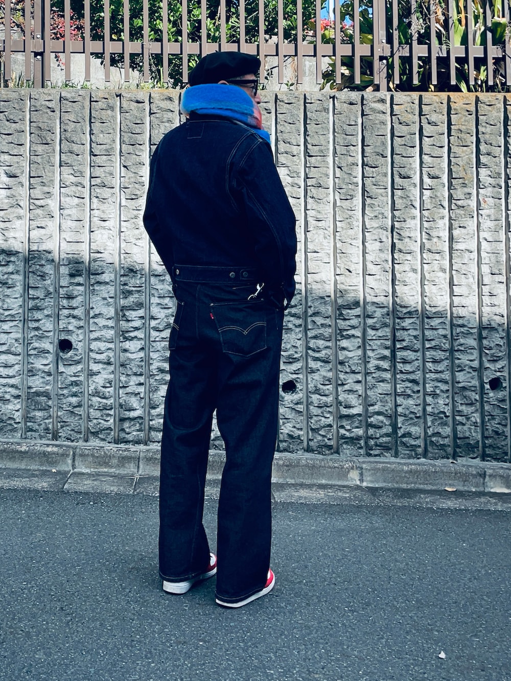 ブルー系のデニムパンツ、ホワイト系のスニーカー、その他のマフラーを着用したメンズの秋コーディネートの2枚目の写真