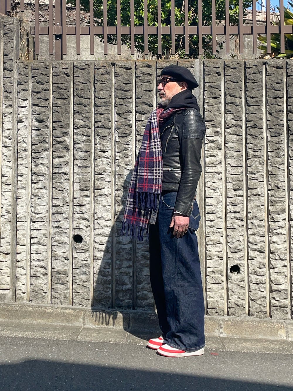 ブルー系のデニムパンツ、ホワイト系のスニーカー、ブラック系のライダースジャケットを着用したメンズの春コーディネートの3枚目の写真