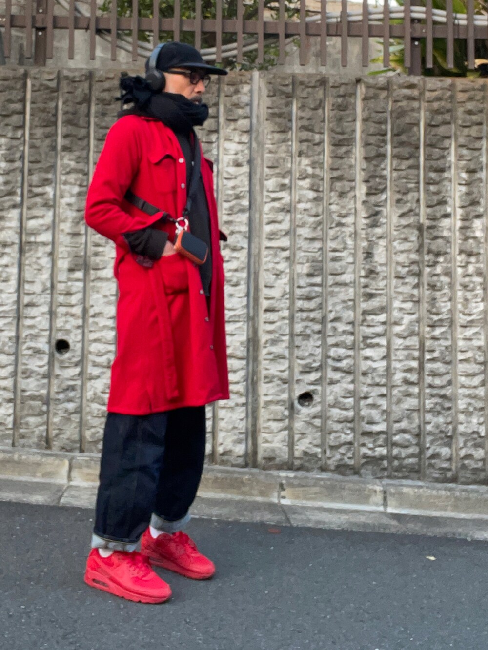 レッド系のステンカラーコート、ブルー系のデニムパンツを着用したメンズの春コーディネートの2枚目の写真