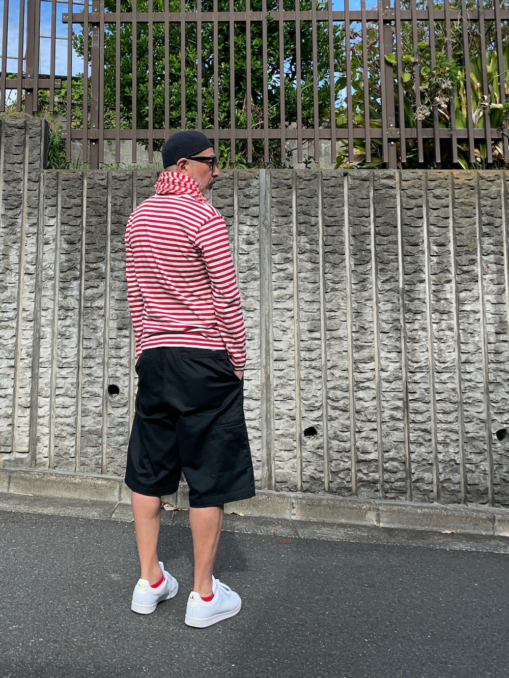 レッド系のTシャツ/カットソー、ブラック系のパンツ、ホワイト系のスニーカーを着用したメンズの秋コーディネートの3枚目の写真