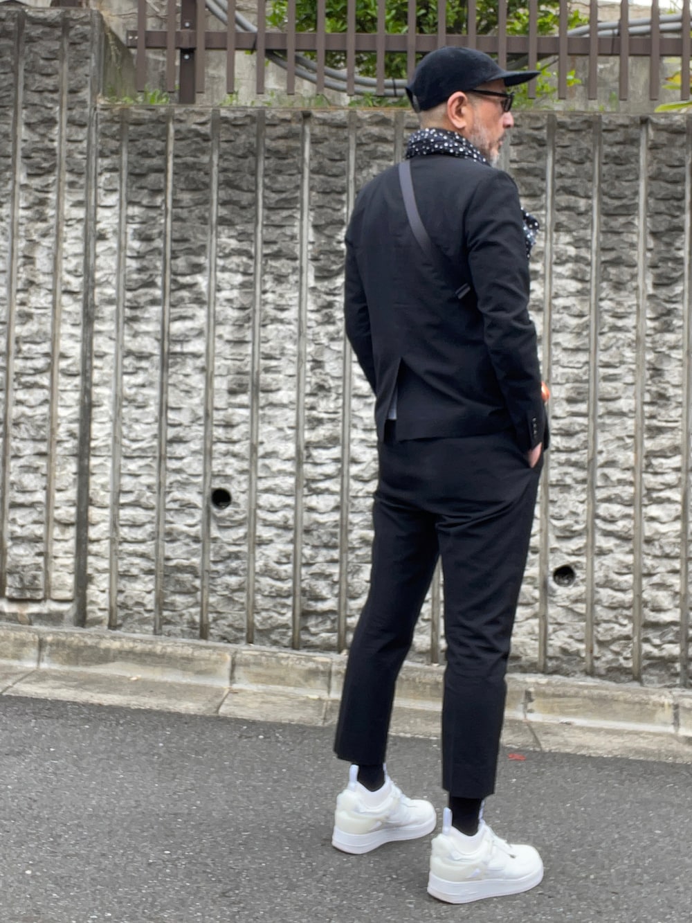 ブラック系のテーラードジャケット、ホワイト系のスニーカー、ブラック系のソックス/靴下を着用したメンズの春コーディネートの2枚目の写真