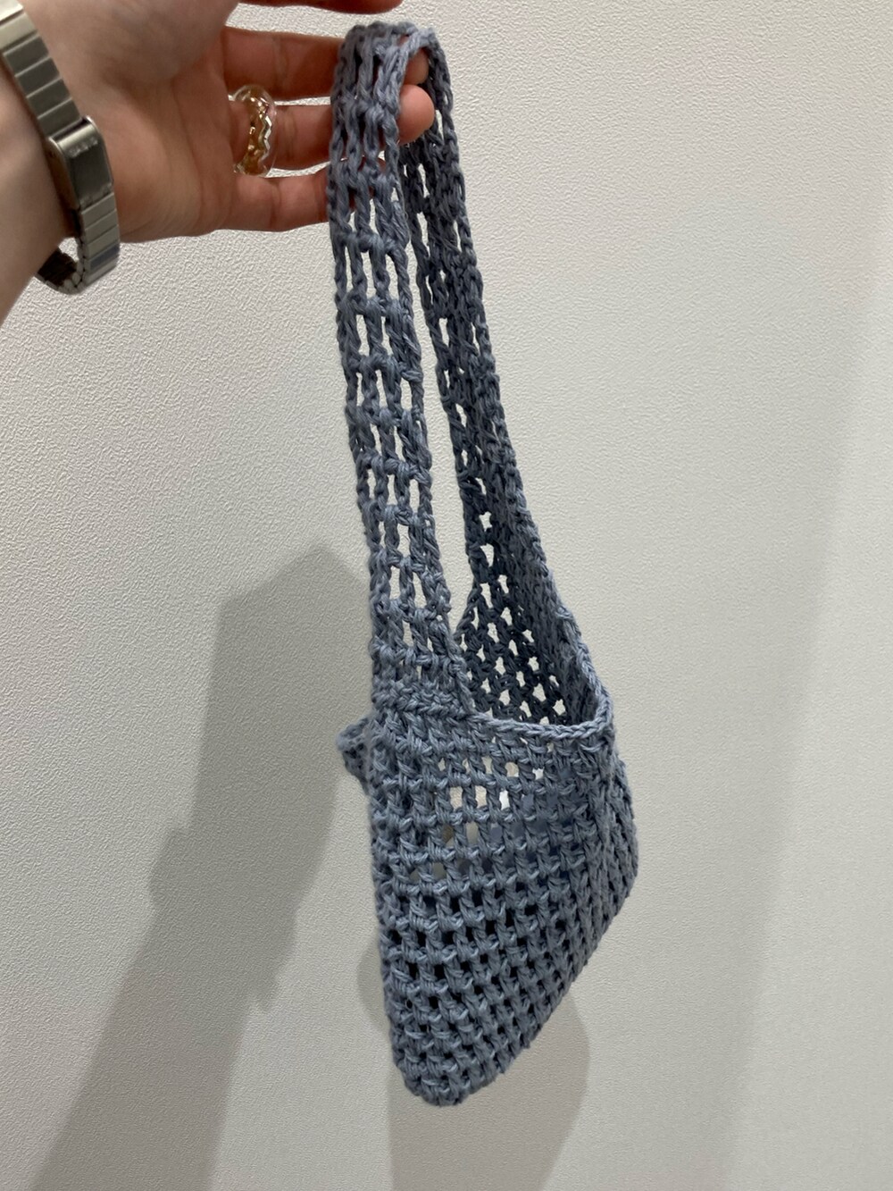 ブラック系のワンピース、ブルー系のハンドバッグ、シルバー系のデジタル腕時計を着用したレディースの春コーディネートの2枚目の写真