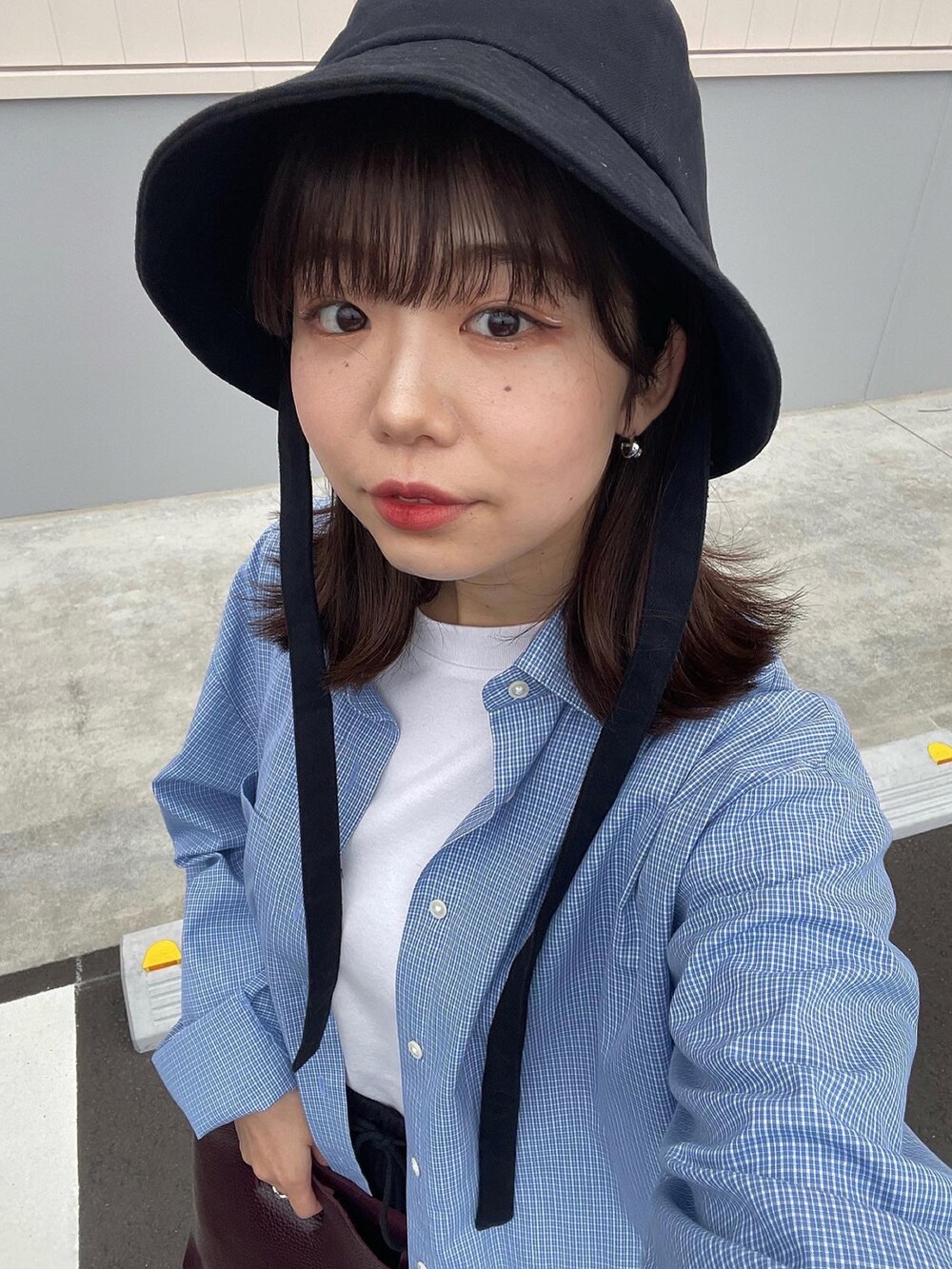 ブラウン系のハンドバッグ、ホワイト系のスニーカー、ブラック系のハットを着用したレディースの春コーディネートの3枚目の写真