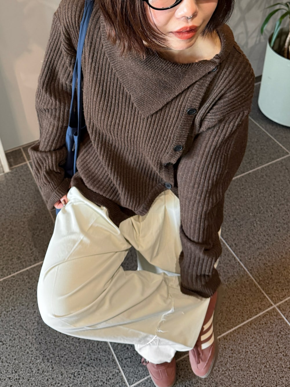 ブラウン系のニット/セーター、ホワイト系のスラックス、ブルー系のショルダーバッグを着用したレディースの冬コーディネートの2枚目の写真