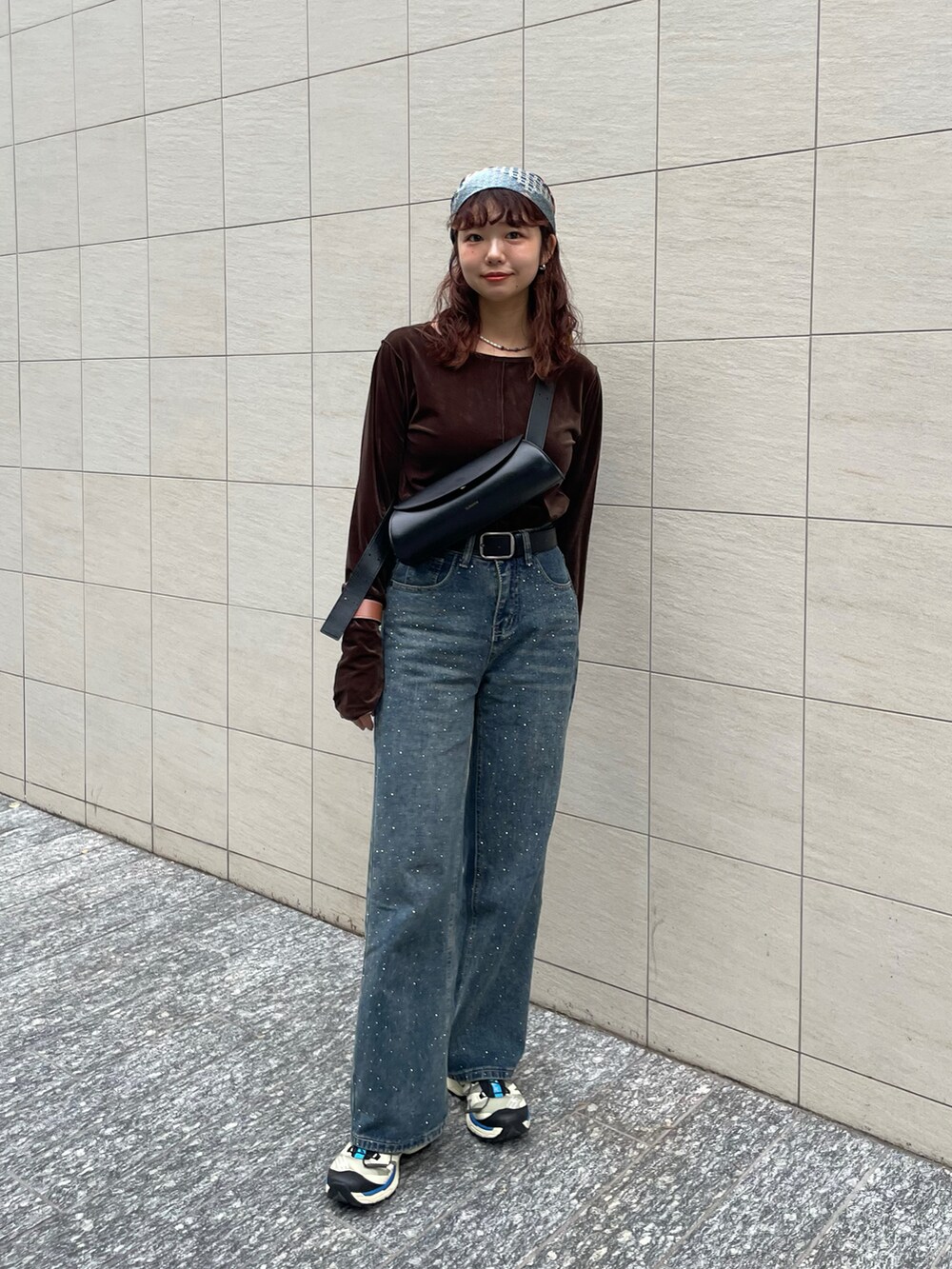 ブラウン系のTシャツ/カットソー、ブラック系のショルダーバッグ、ブルー系のデニムパンツを着用したレディースの秋コーディネートの3枚目の写真