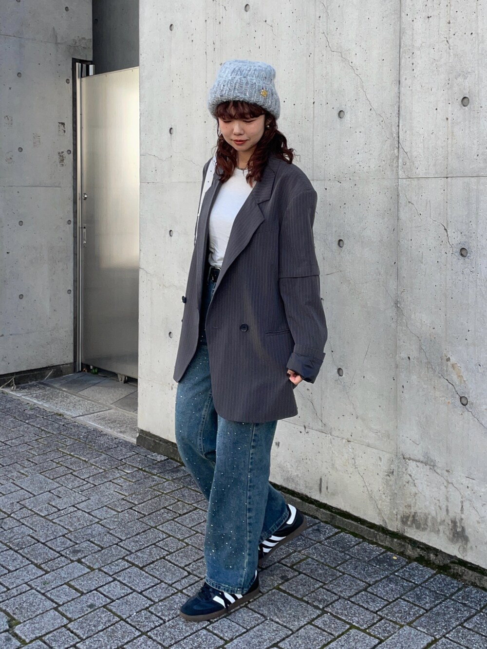 グレー系のテーラードジャケット、ブルー系のデニムパンツ、ブラック系のスニーカーを着用したレディースの秋コーディネートの2枚目の写真